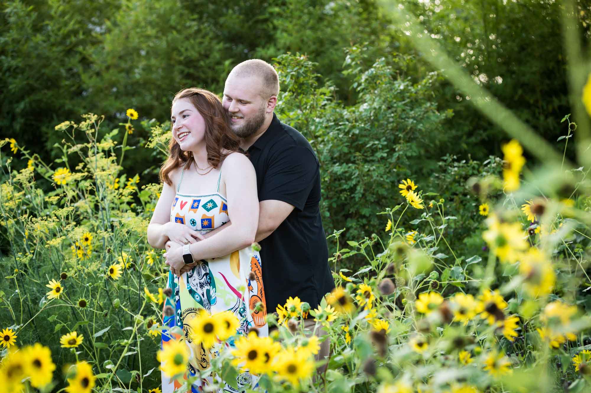 Couple hugging in flower garden of sunflowers during a Landa Library engagement portrait