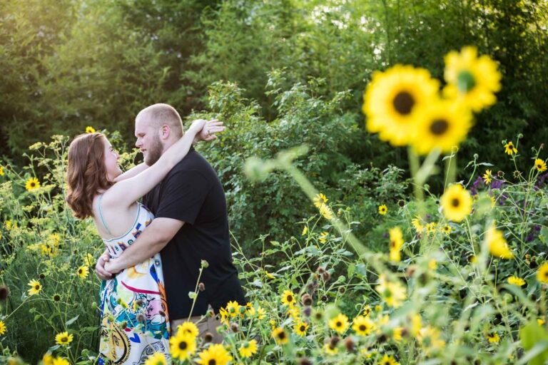 Couple hugging in flower garden of sunflowers during a Landa Library engagement portrait