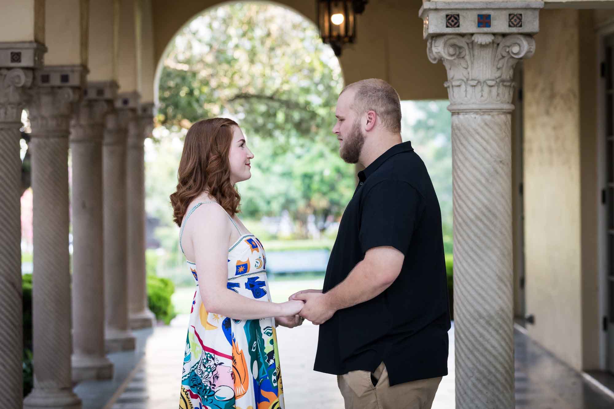 Couple holding hands in front of colonnade for an article on how to propose at the Landa Library