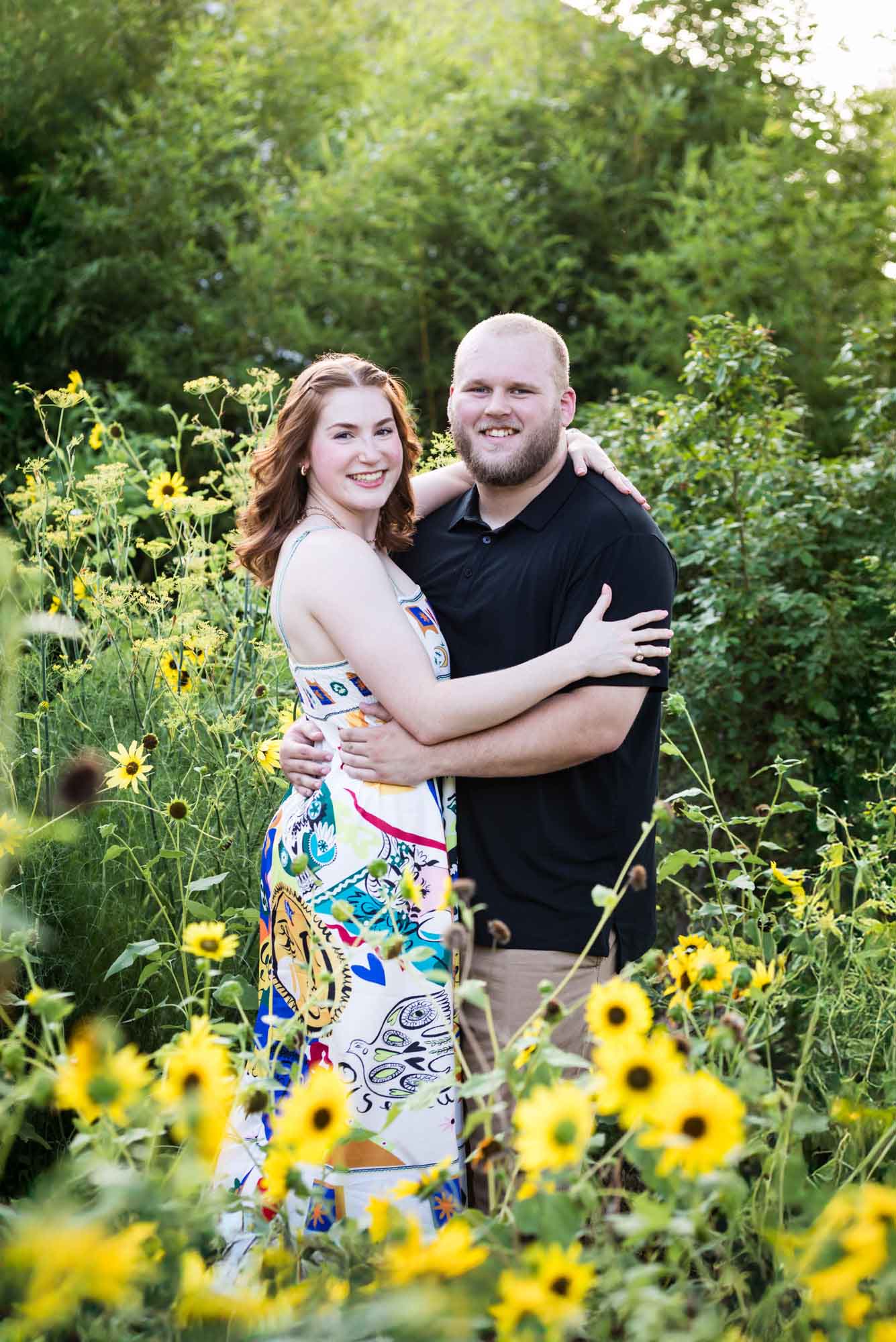 Couple hugging in flower garden of sunflowers during a Landa Library engagement portrait