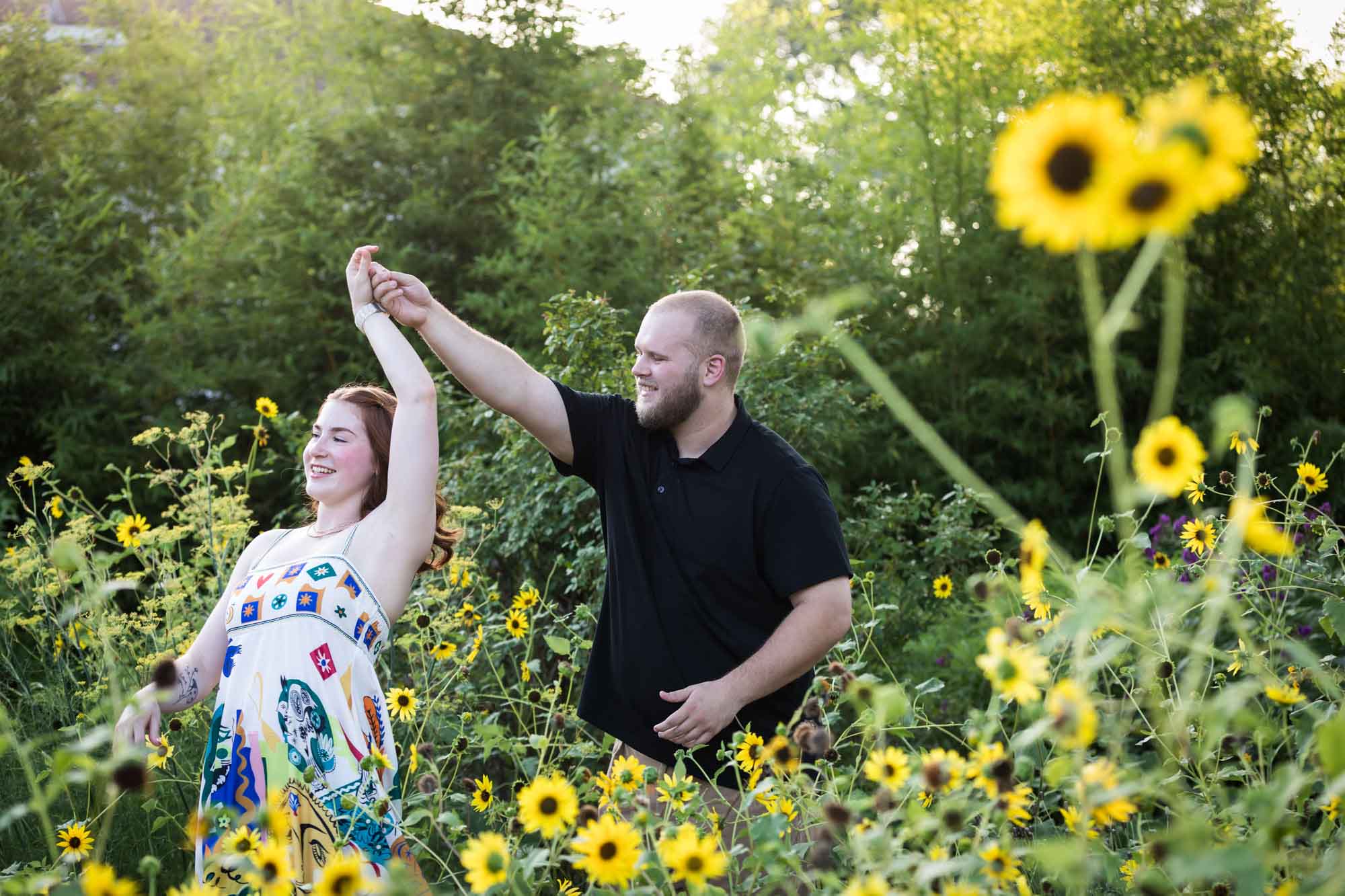 Couple dancing in flower garden of sunflowers during a Landa Library engagement portrait