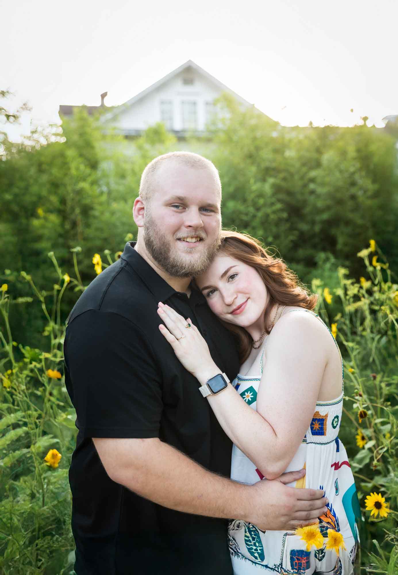 Couple hugging in flower garden of sunflowers during a Landa Library engagement portrait