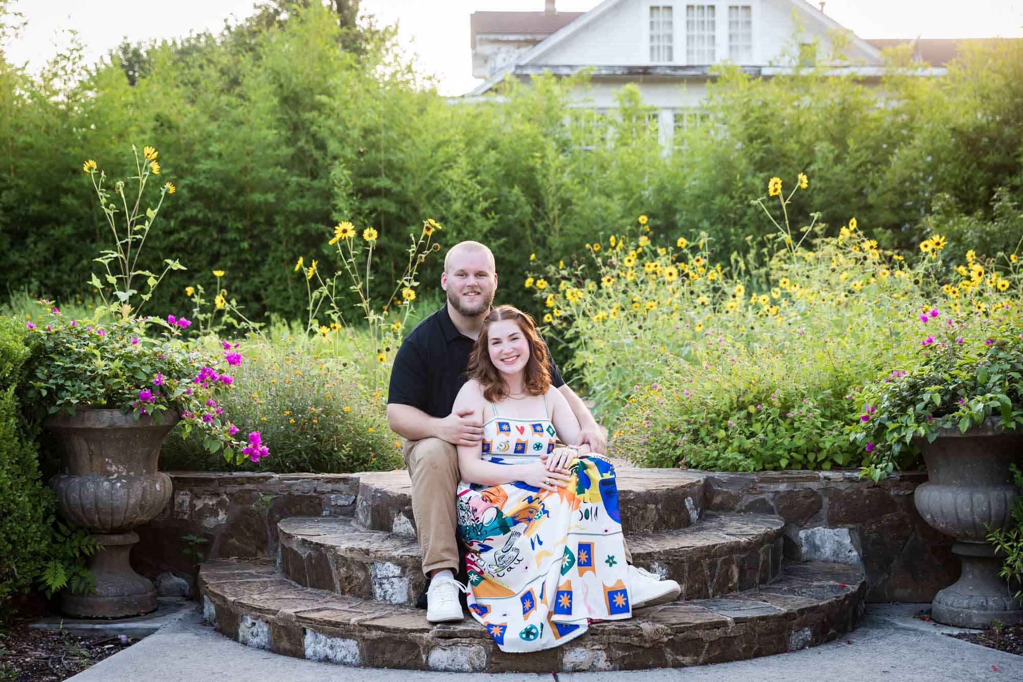 Couple sitting on brick steps in flower garden after a Landa Library proposal