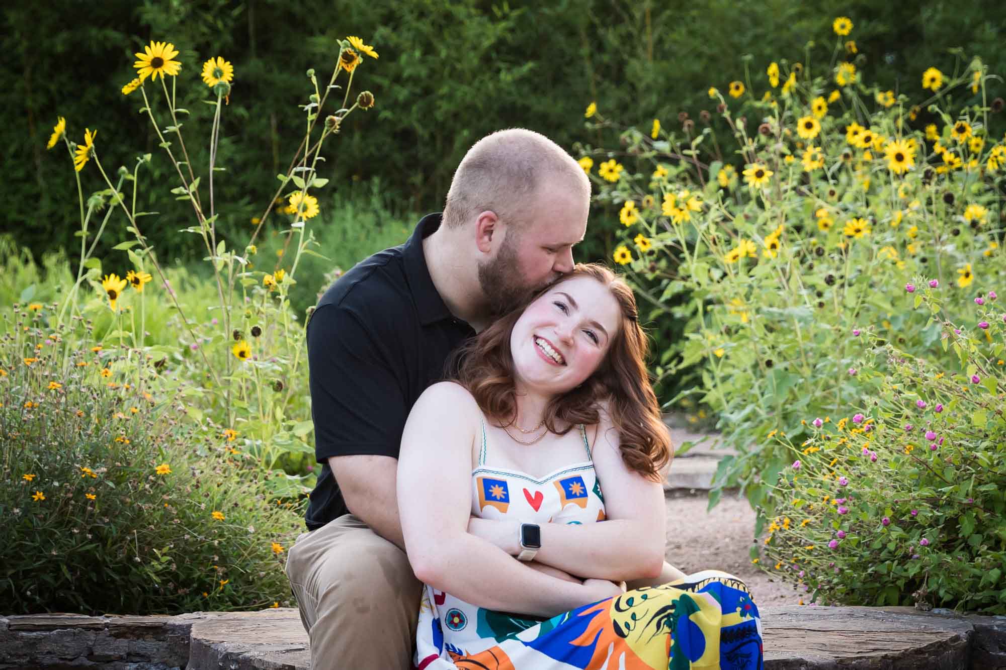 Couple sitting on brick steps in flower garden after a Landa Library proposal