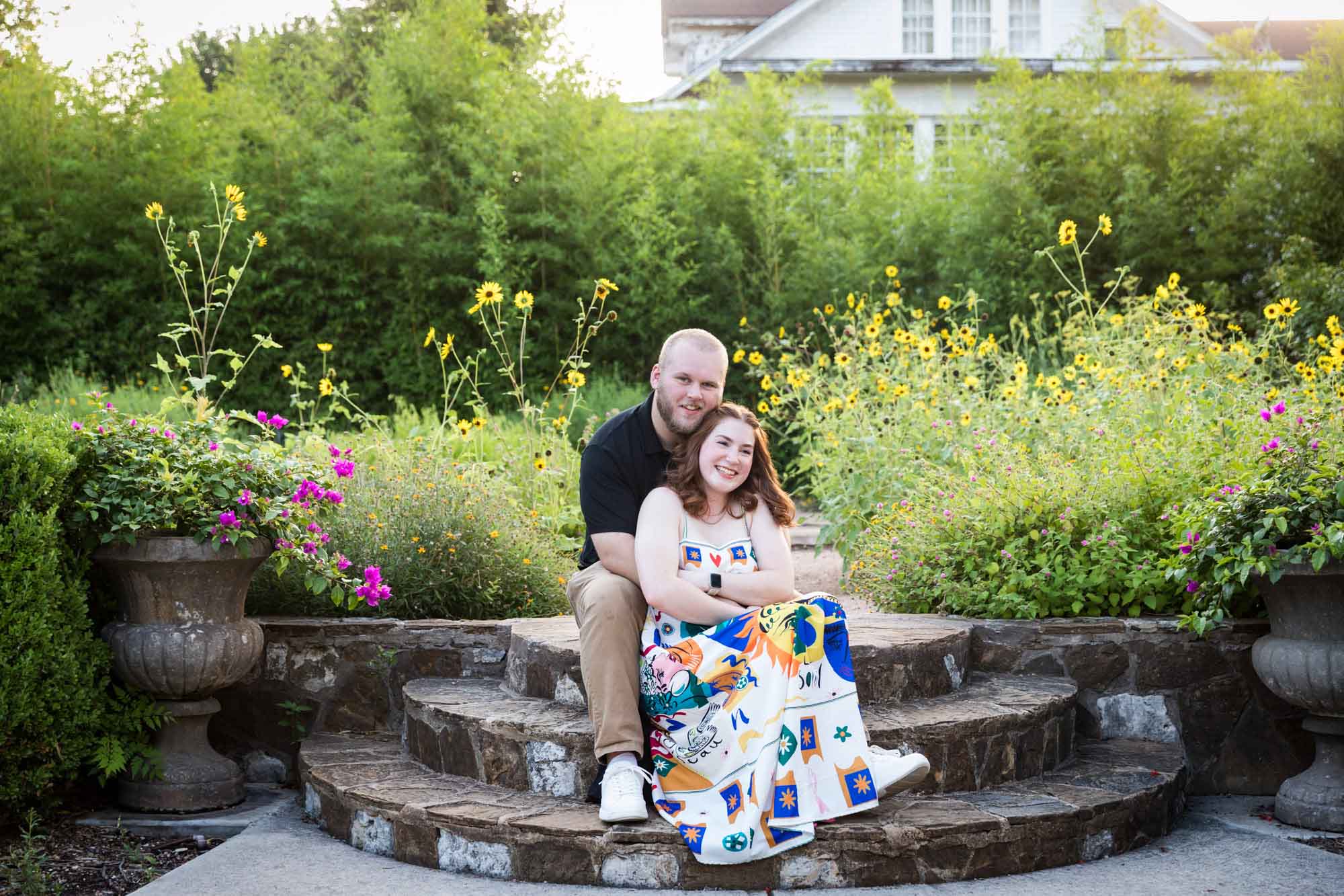 Couple sitting on brick steps in flower garden after a Landa Library proposal