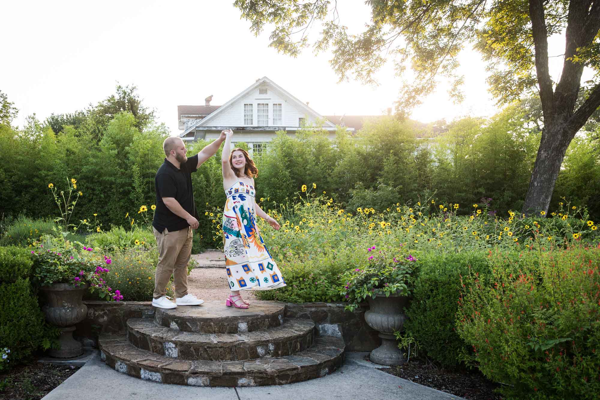 Couple dancing on brick steps in flower garden after a Landa Library proposal