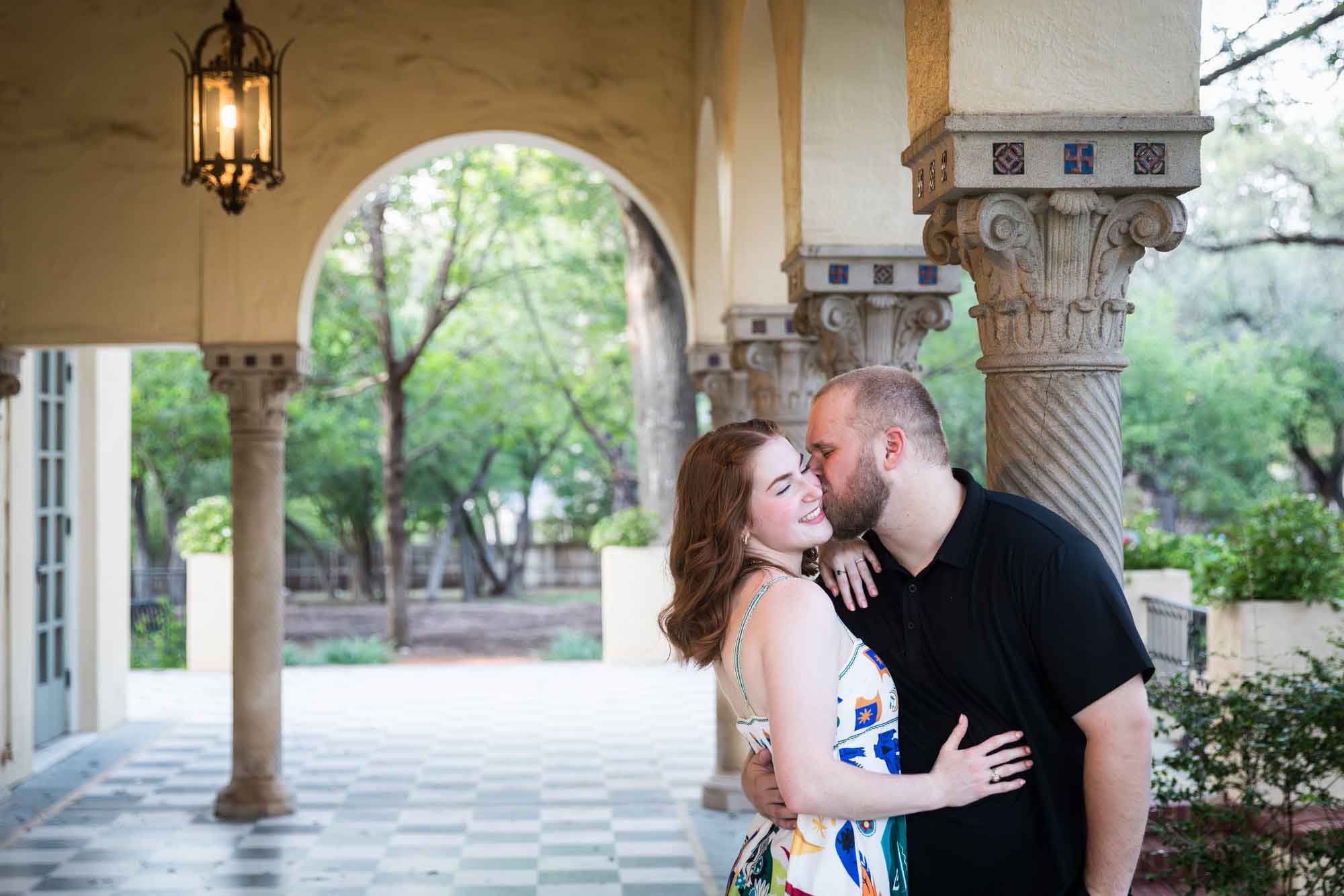 Couple kissing beside concrete column for an article on how to propose at the Landa Library