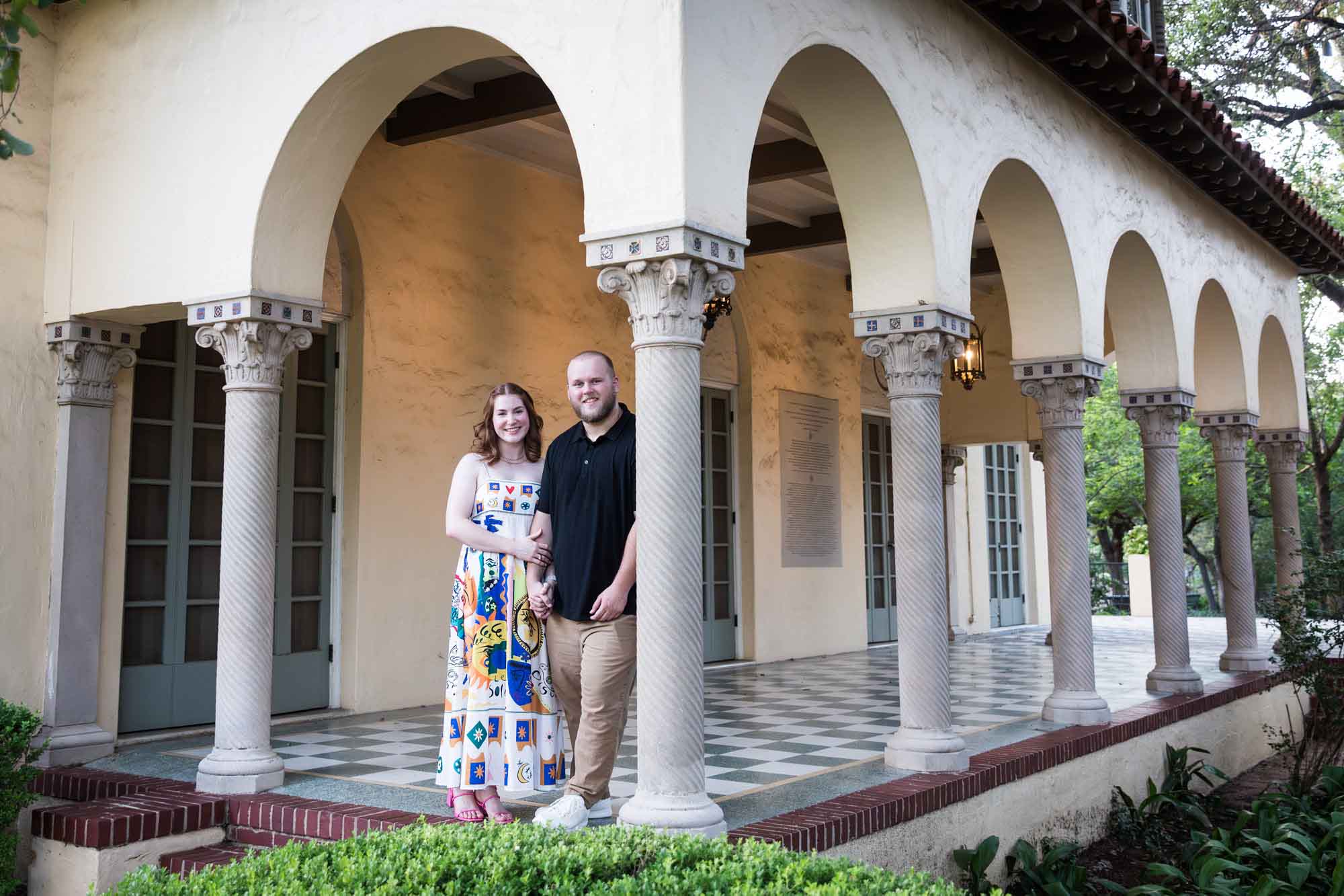 Couple standing beside concrete column for an article on how to propose at the Landa Library