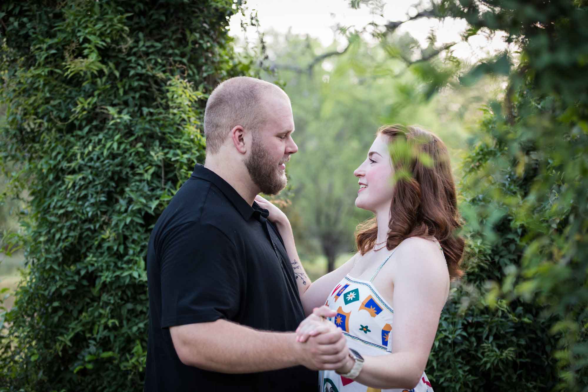 Couple dancing in front of vine-covered trees during a Landa Library engagement portrait