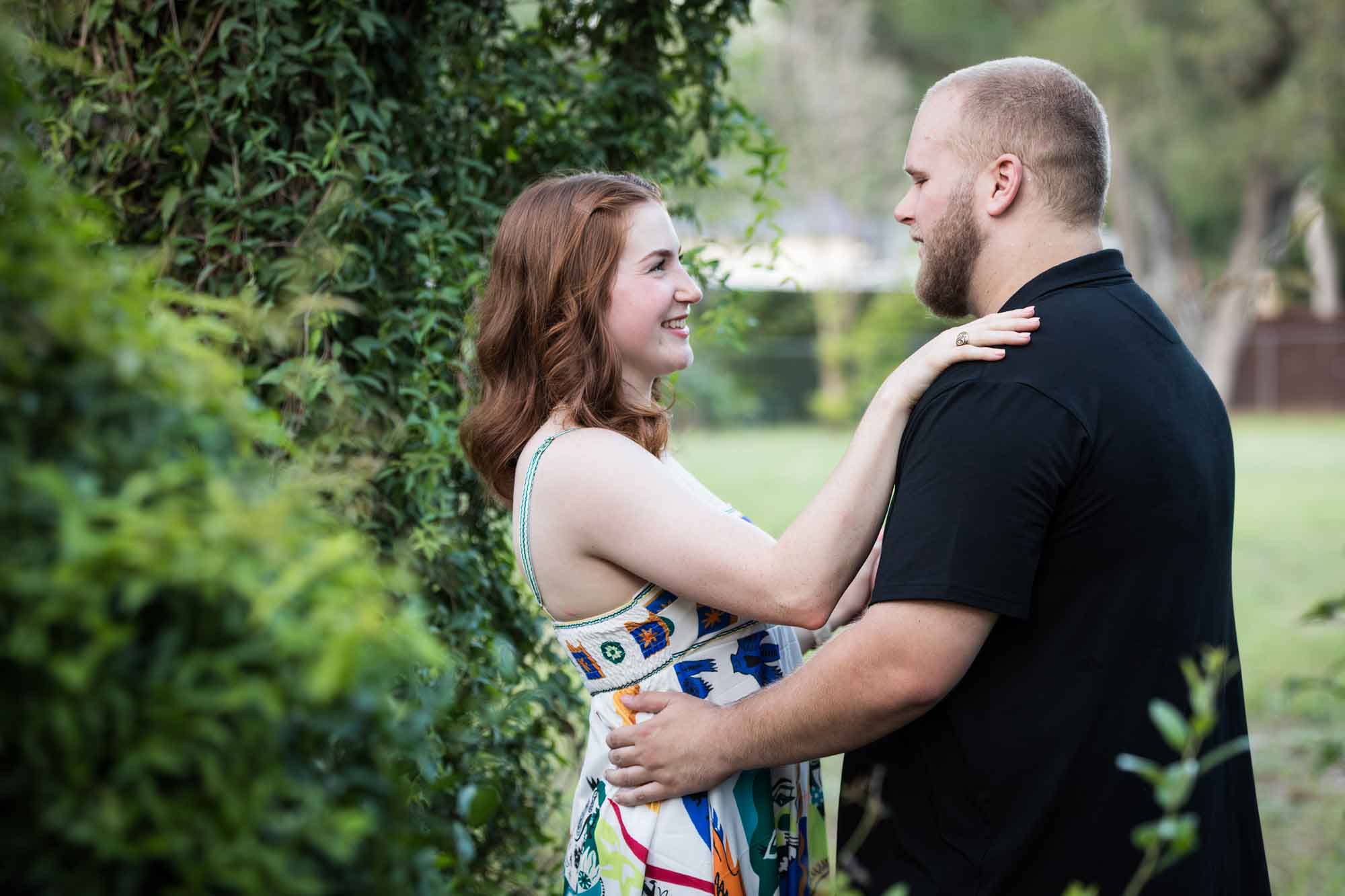 Couple dancing in front of vine-covered trees during a Landa Library engagement portrait
