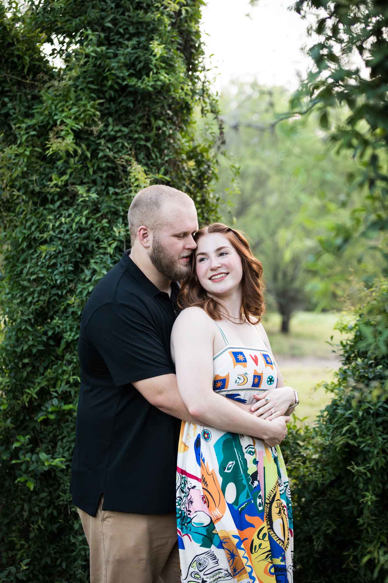 Couple dancing in front of vine-covered trees during a Landa Library engagement portrait