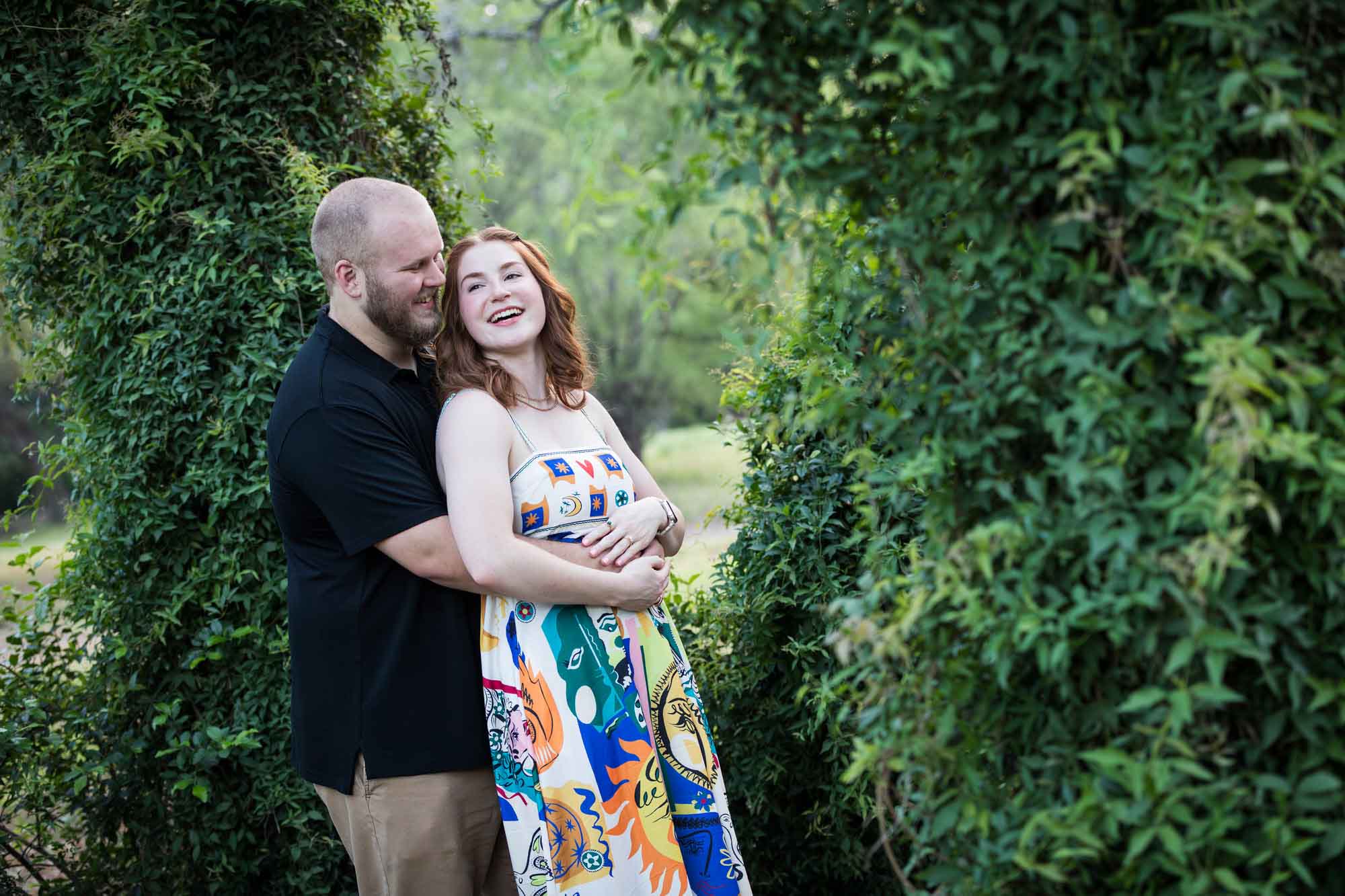 Couple dancing in front of vine-covered trees during a Landa Library engagement portrait