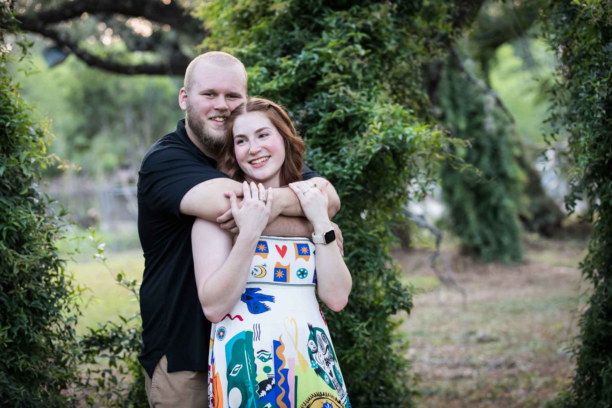Couple dancing in front of vine-covered trees during a Landa Library engagement portrait