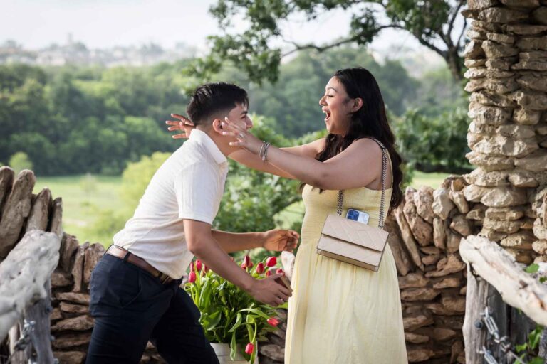 Man wearing black pants bending down on one knee in front of woman wearing yellow dress in stone gazebo during proposal for an article on Japanese Tea Garden proposal tips