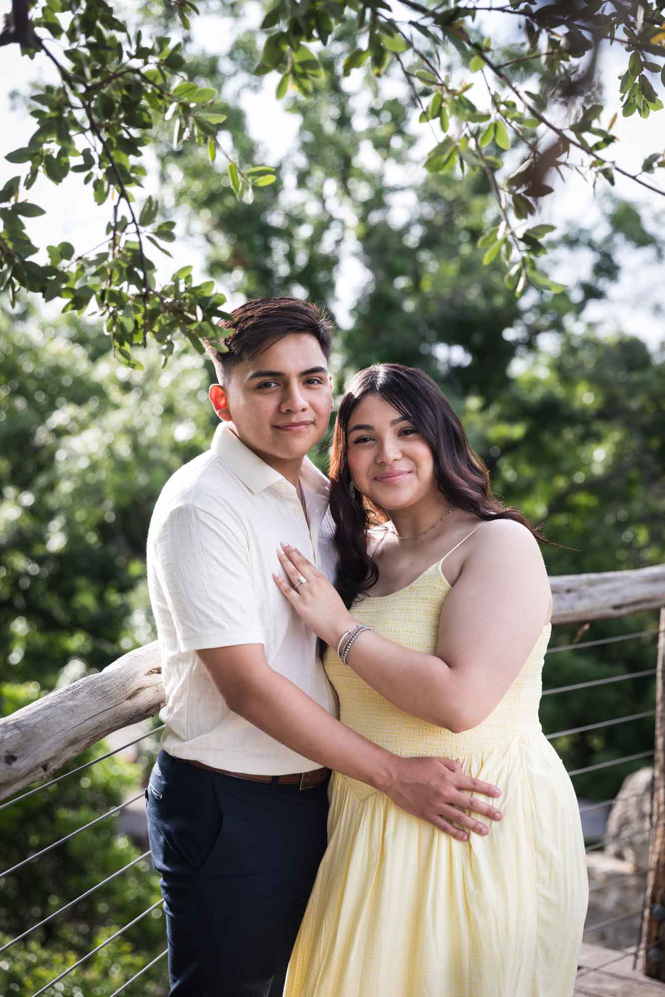 Man wearing white shirt hugging woman wearing yellow dress during a Japanese Tea Garden engagement portrait