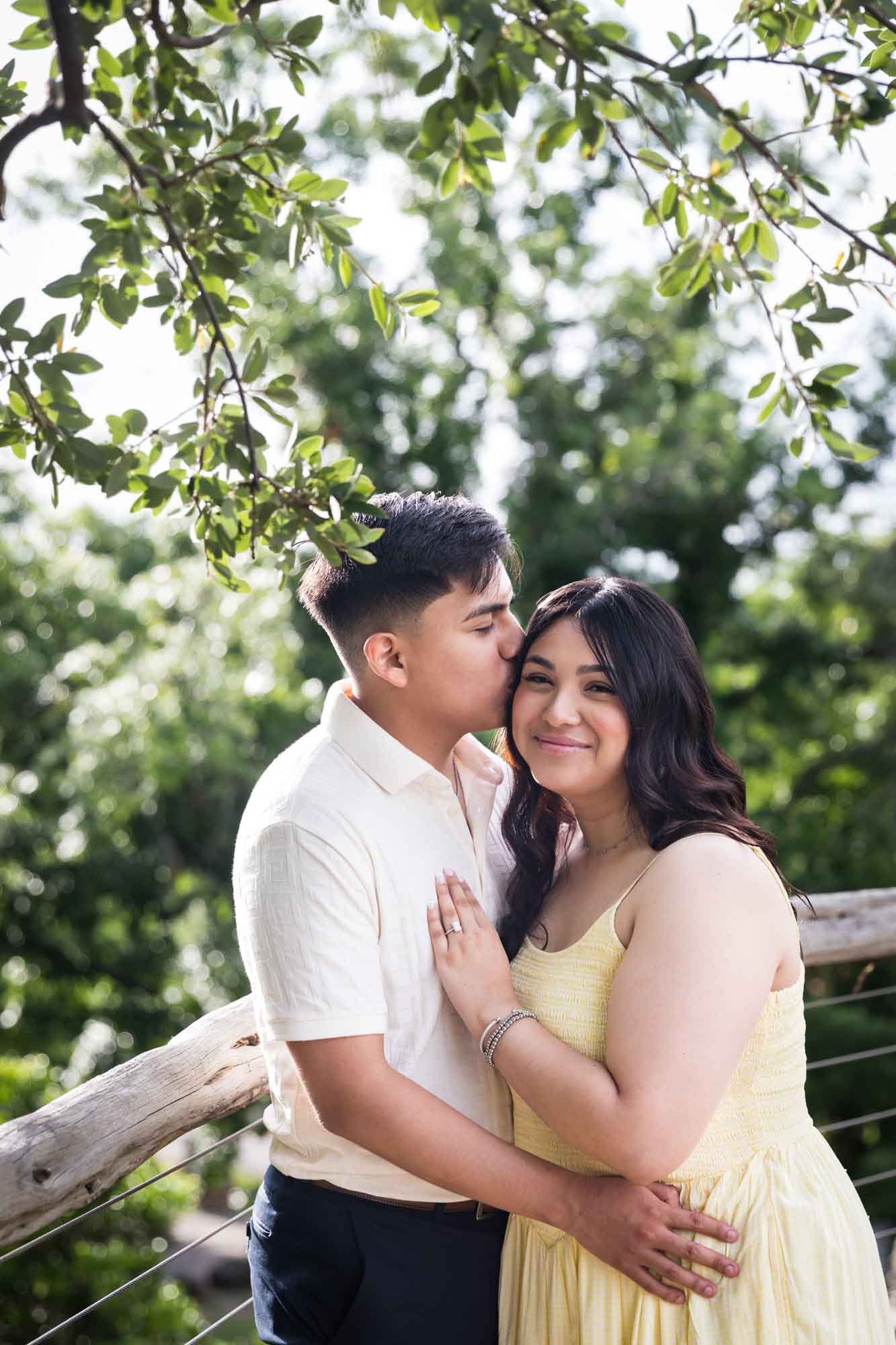 Man wearing white shirt kissing woman wearing yellow dress during a Japanese Tea Garden engagement portrait