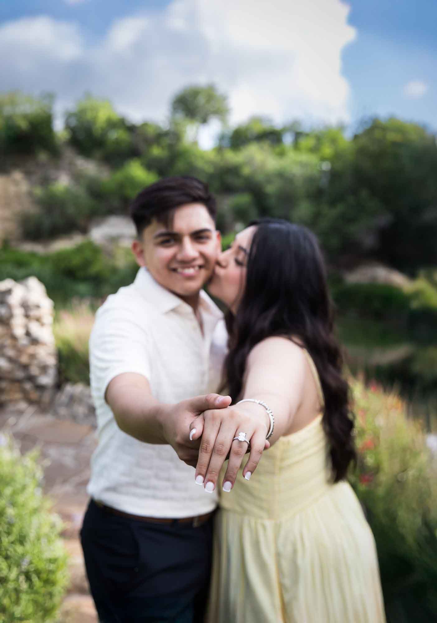Man wearing white shirt holding out hand with woman wearing yellow dress during a Japanese Tea Garden engagement portrait