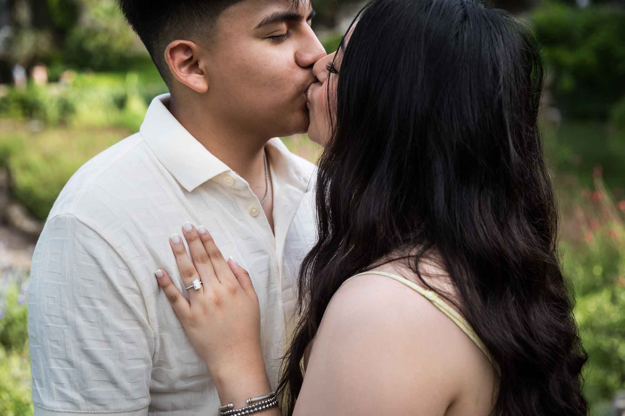Man wearing white shirt kissing woman wearing yellow dress during a Japanese Tea Garden engagement portrait