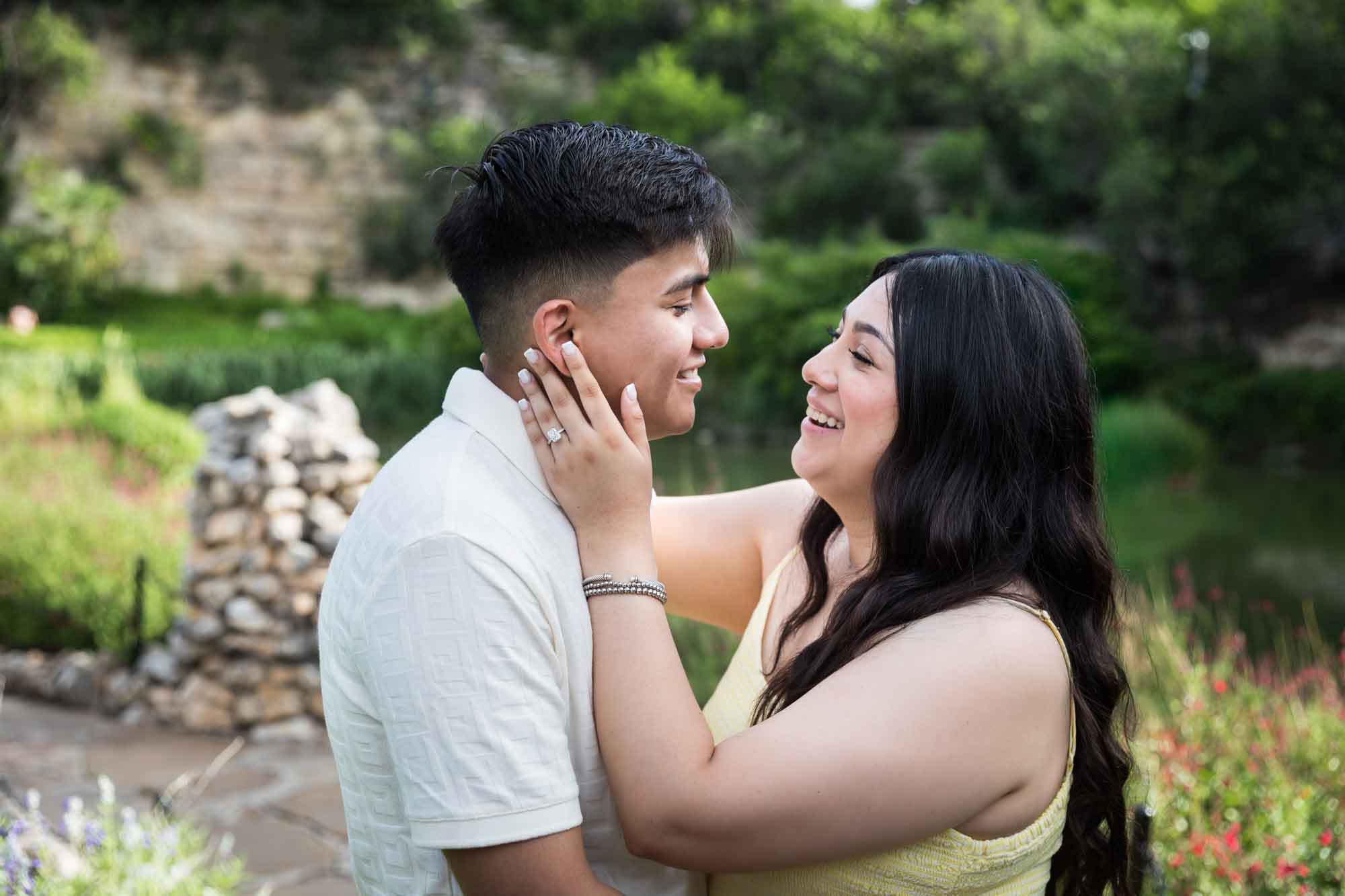 Man wearing white shirt hugging woman wearing yellow dress during a Japanese Tea Garden engagement portrait