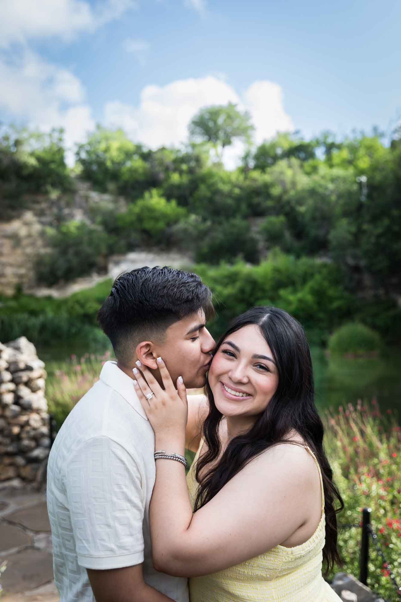 Man wearing white shirt kissing woman wearing yellow dress during a Japanese Tea Garden engagement portrait