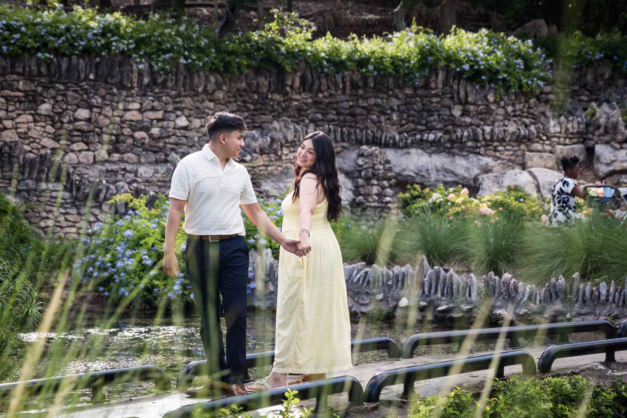 Man wearing white shirt dancing woman wearing yellow dress during a Japanese Tea Garden engagement portrait