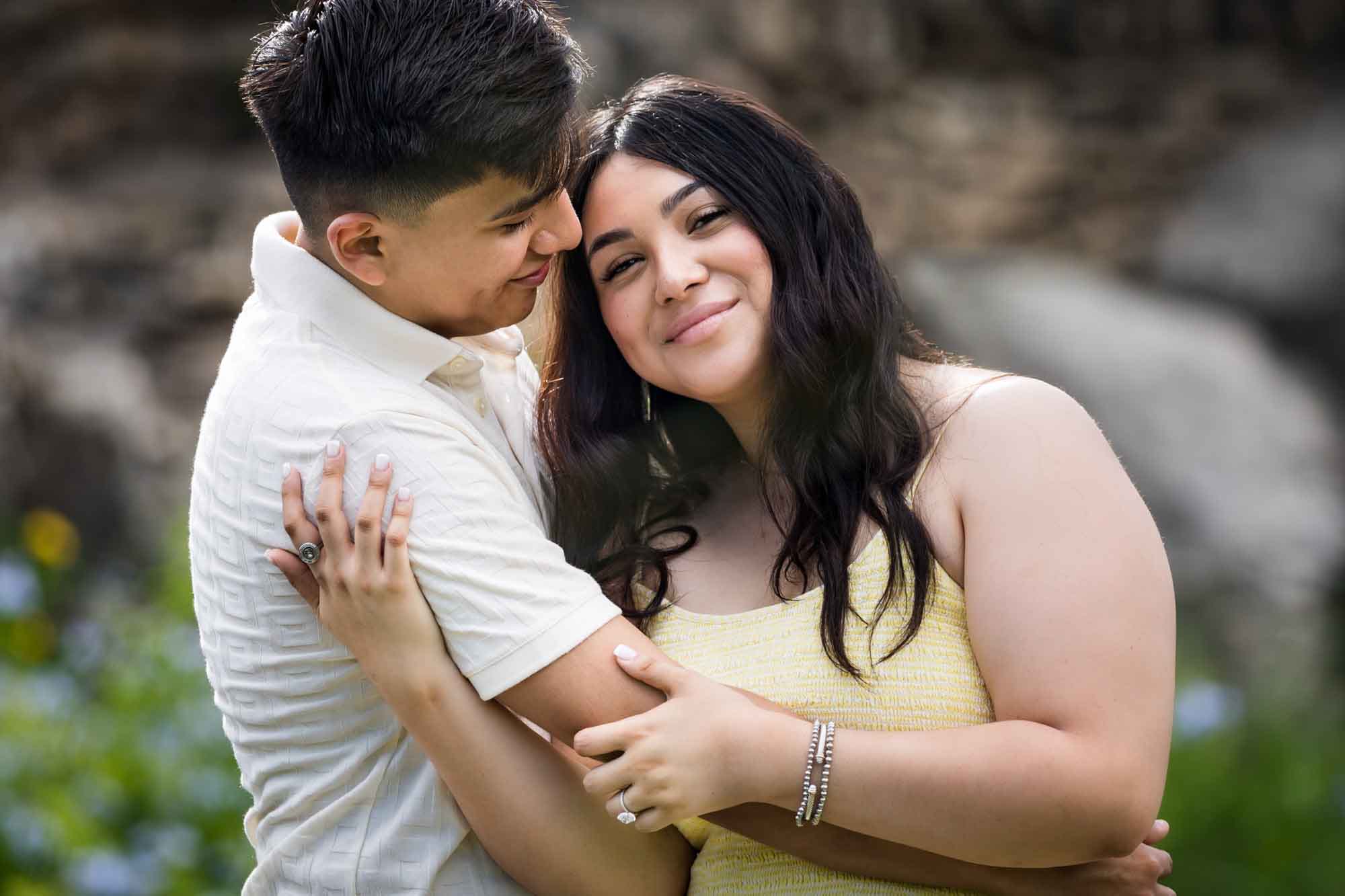 Man wearing white shirt hugging woman wearing yellow dress during a Japanese Tea Garden engagement portrait