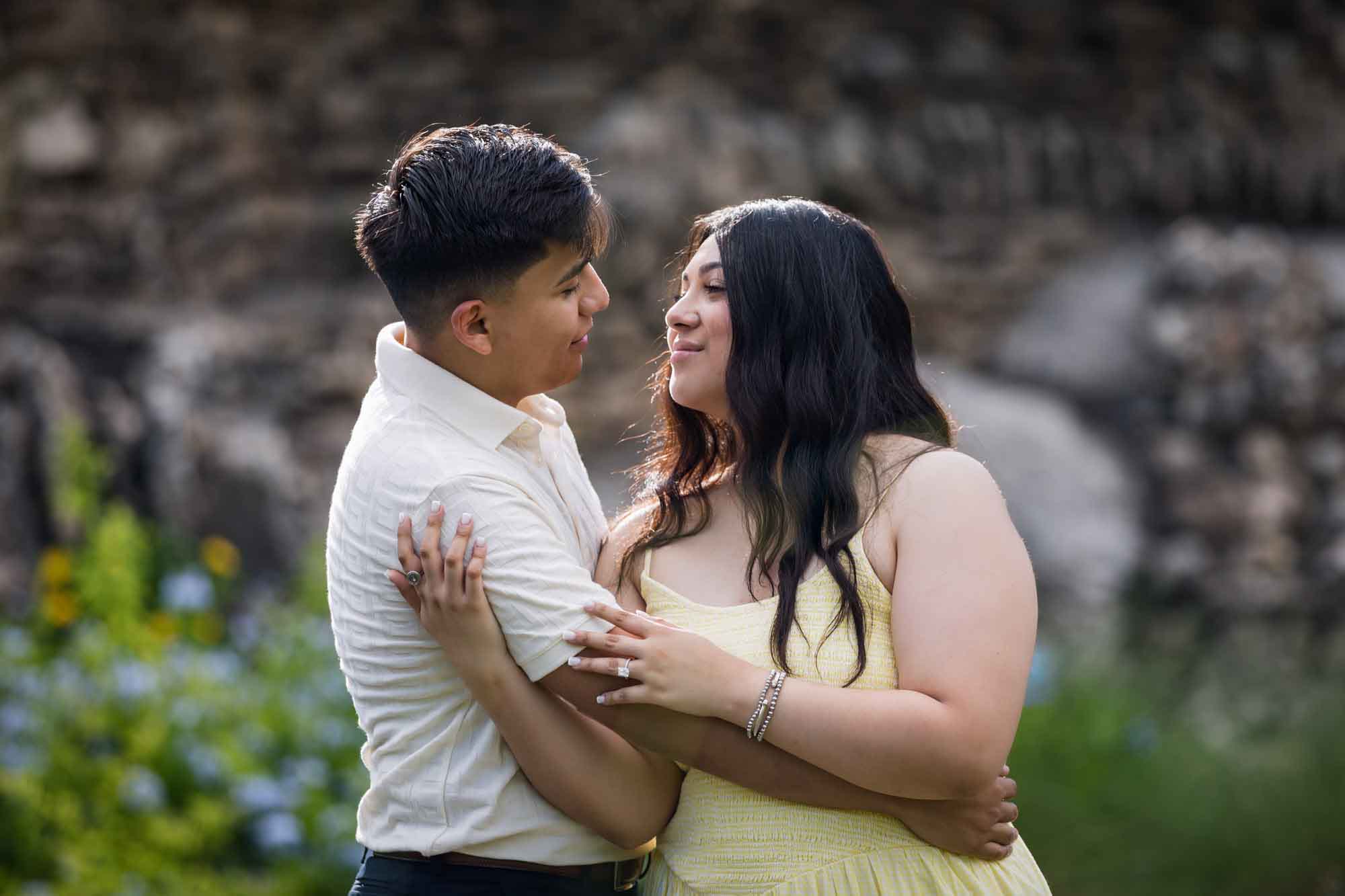 Man wearing white shirt hugging woman wearing yellow dress during a Japanese Tea Garden engagement portrait
