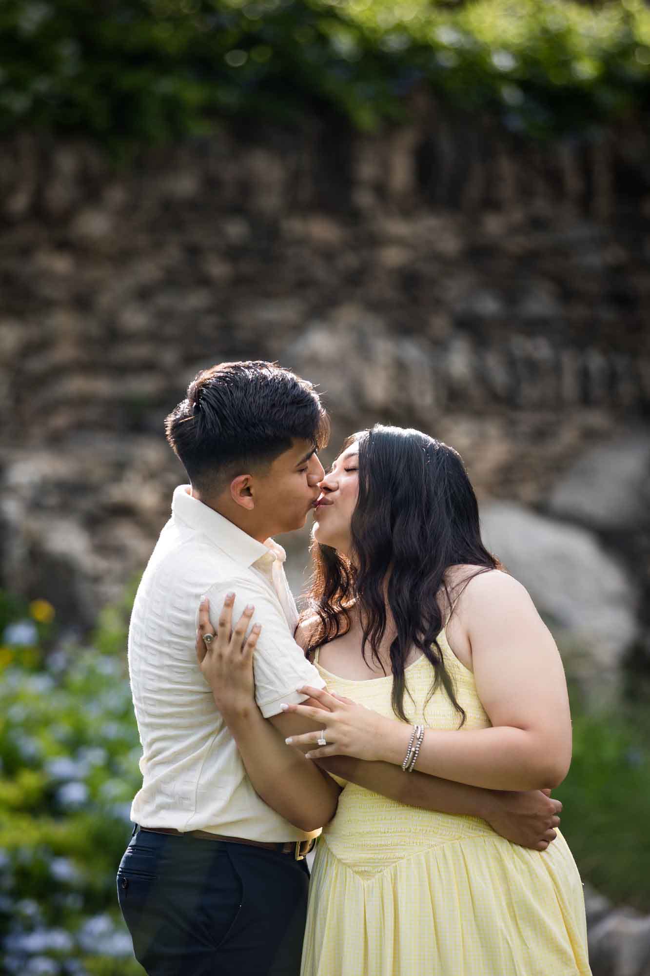 Man wearing white shirt kissing woman wearing yellow dress during a Japanese Tea Garden engagement portrait
