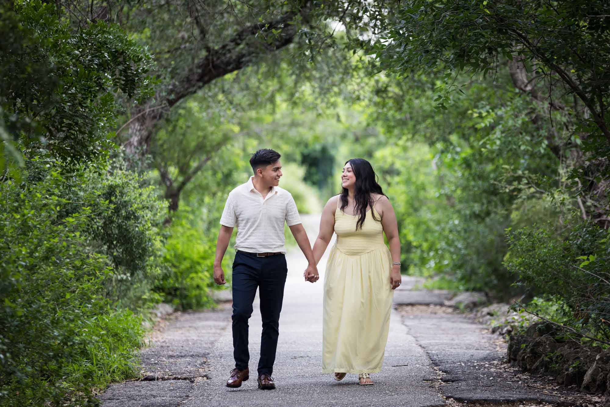 Man wearing white shirt walking with woman wearing yellow dress during a Japanese Tea Garden engagement portrait