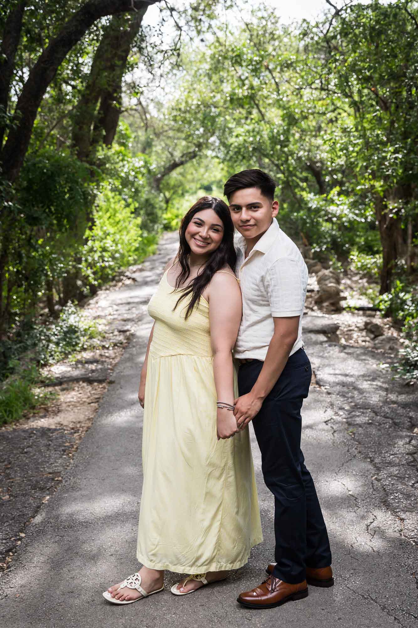 Man wearing white shirt holding hands with woman wearing yellow dress during a Japanese Tea Garden engagement portrait