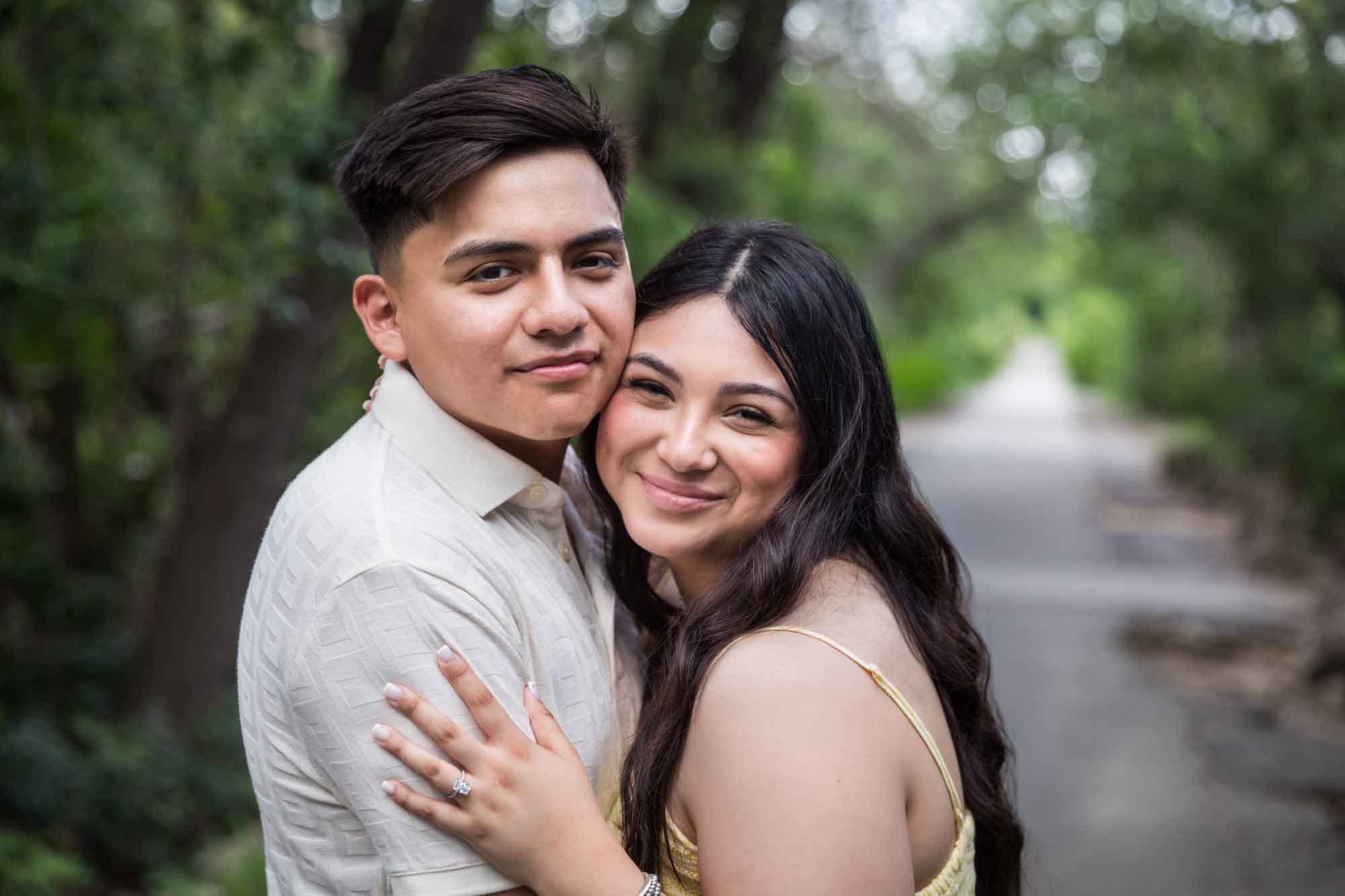 Man wearing white shirt hugging woman wearing yellow dress during a Japanese Tea Garden engagement portrait