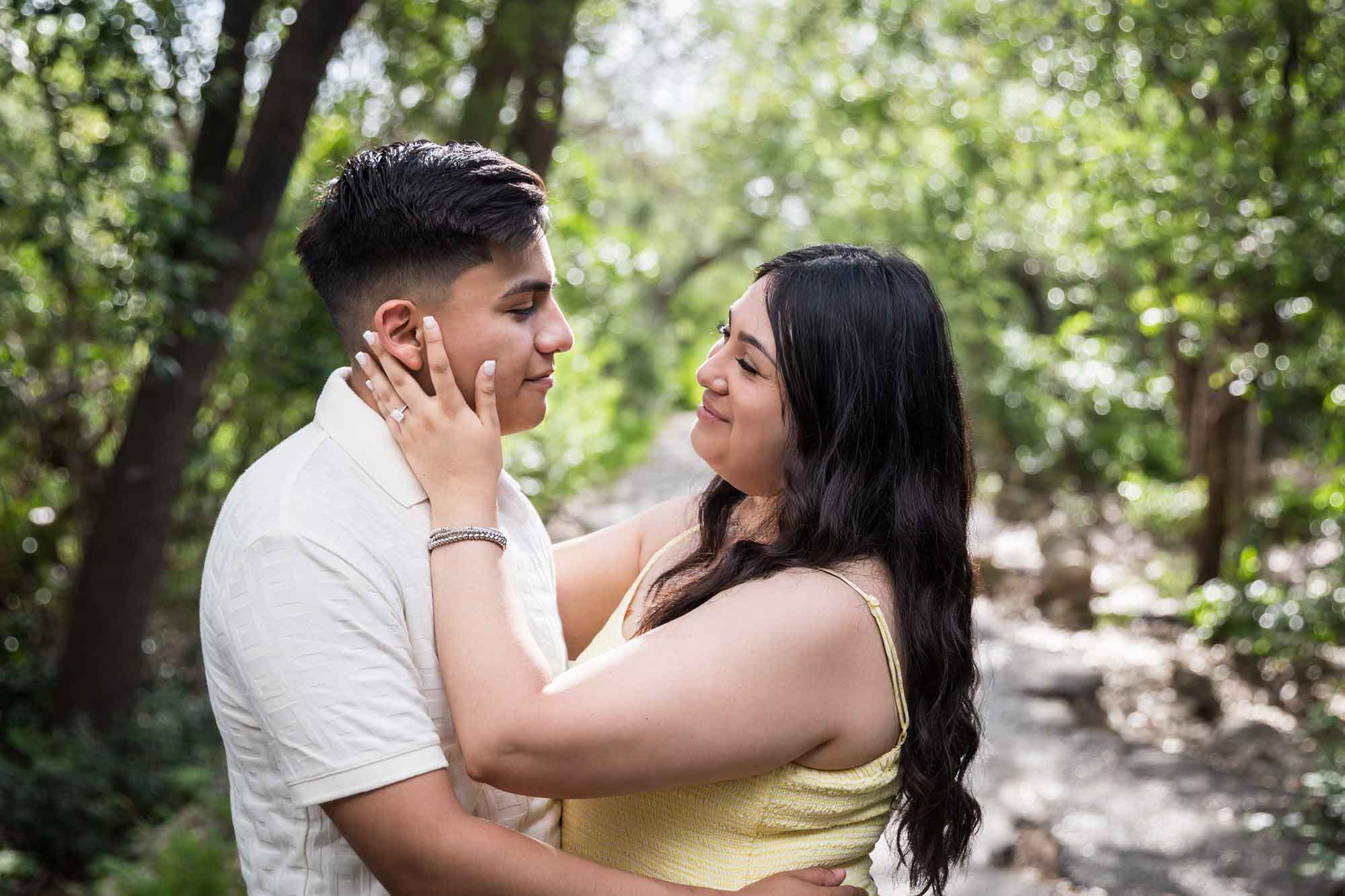 Man wearing white shirt hugging woman wearing yellow dress during a Japanese Tea Garden engagement portrait
