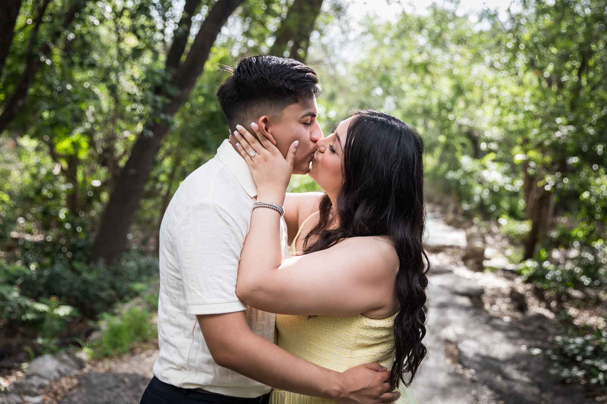 Man wearing white shirt kissing woman wearing yellow dress during a Japanese Tea Garden engagement portrait