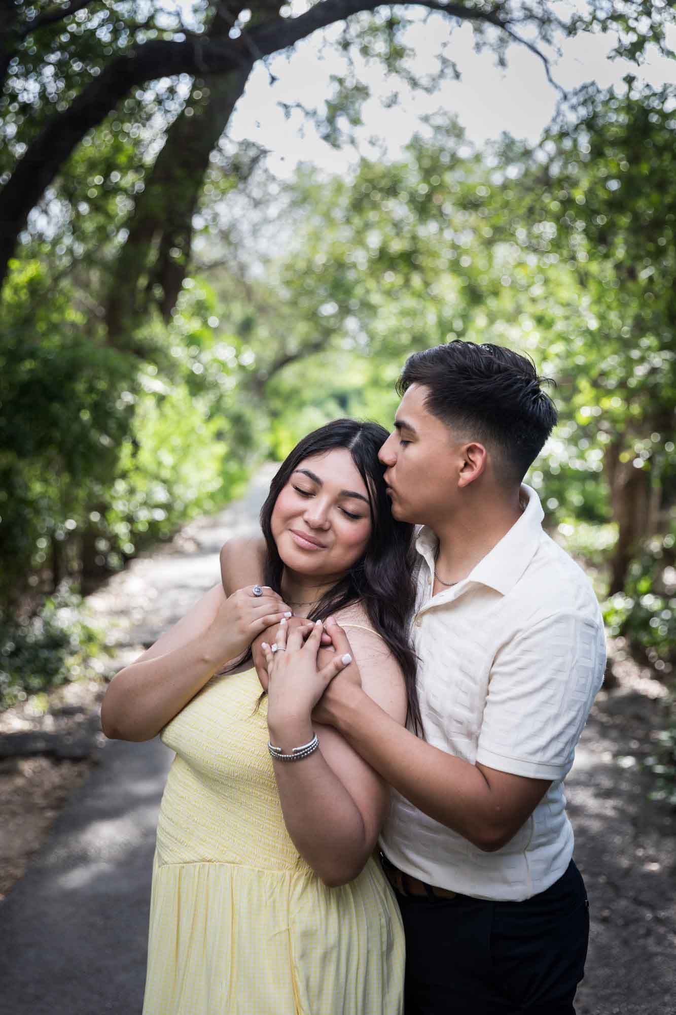 Man wearing white shirt kissing woman wearing yellow dress during a Japanese Tea Garden engagement portrait