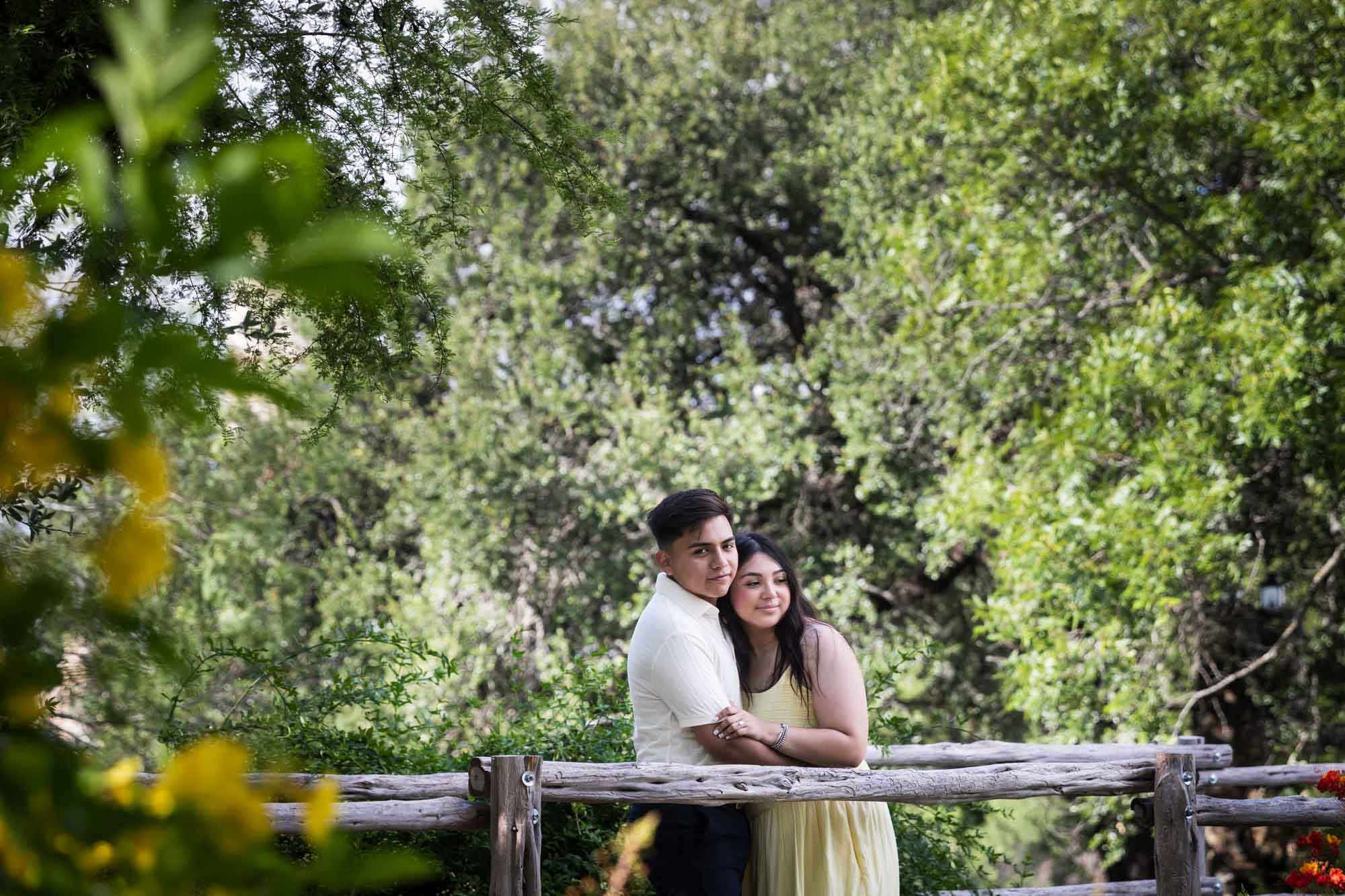 Man wearing white shirt hugging woman wearing yellow dress during a Japanese Tea Garden engagement portrait
