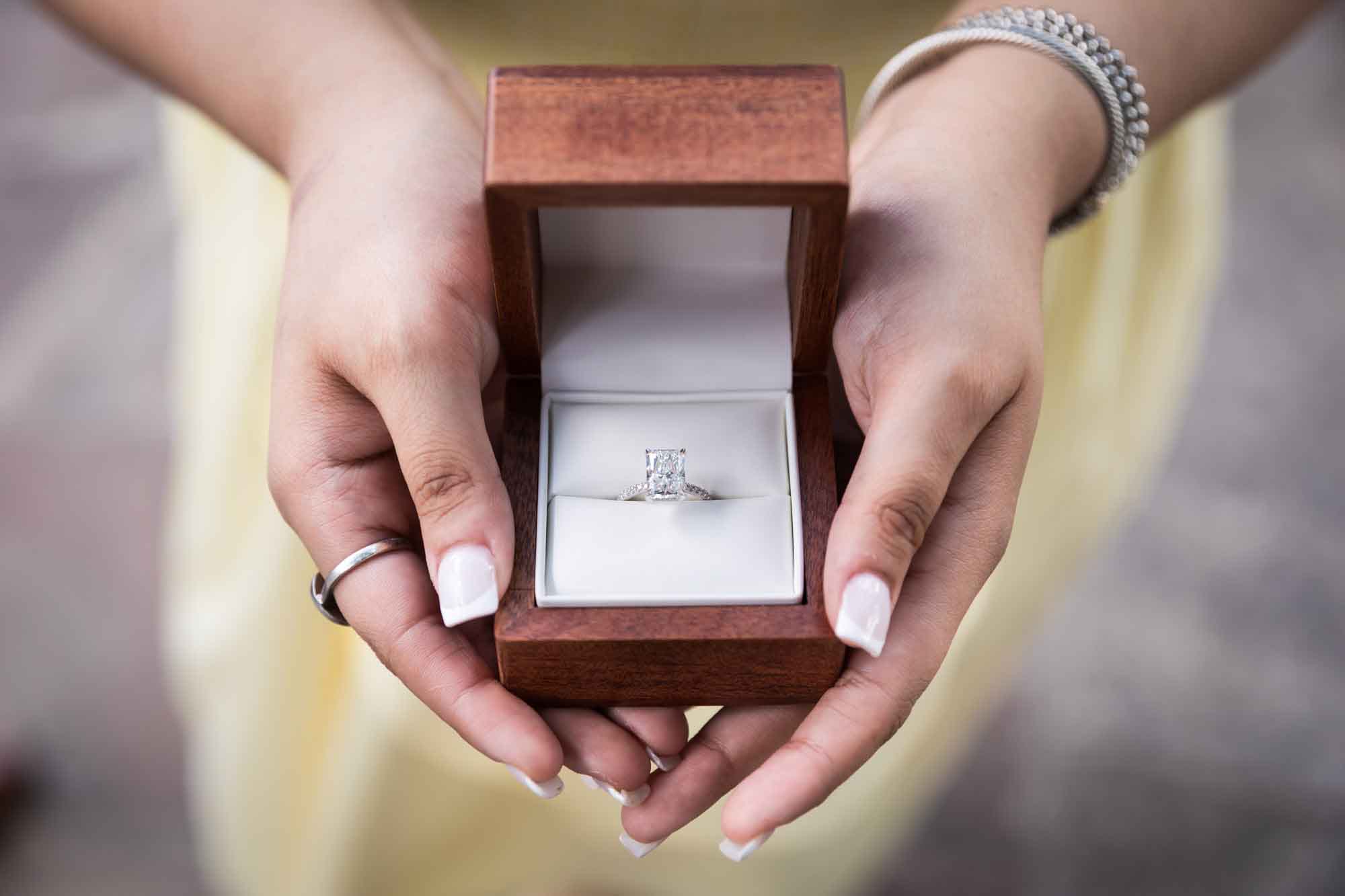 Close up of woman's hands holding wooden box with engagement ring