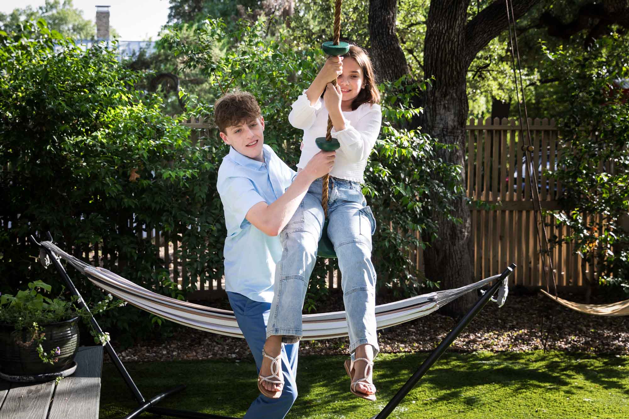 Teenage boy and girl playing on swing in backyard during a King William family portrait