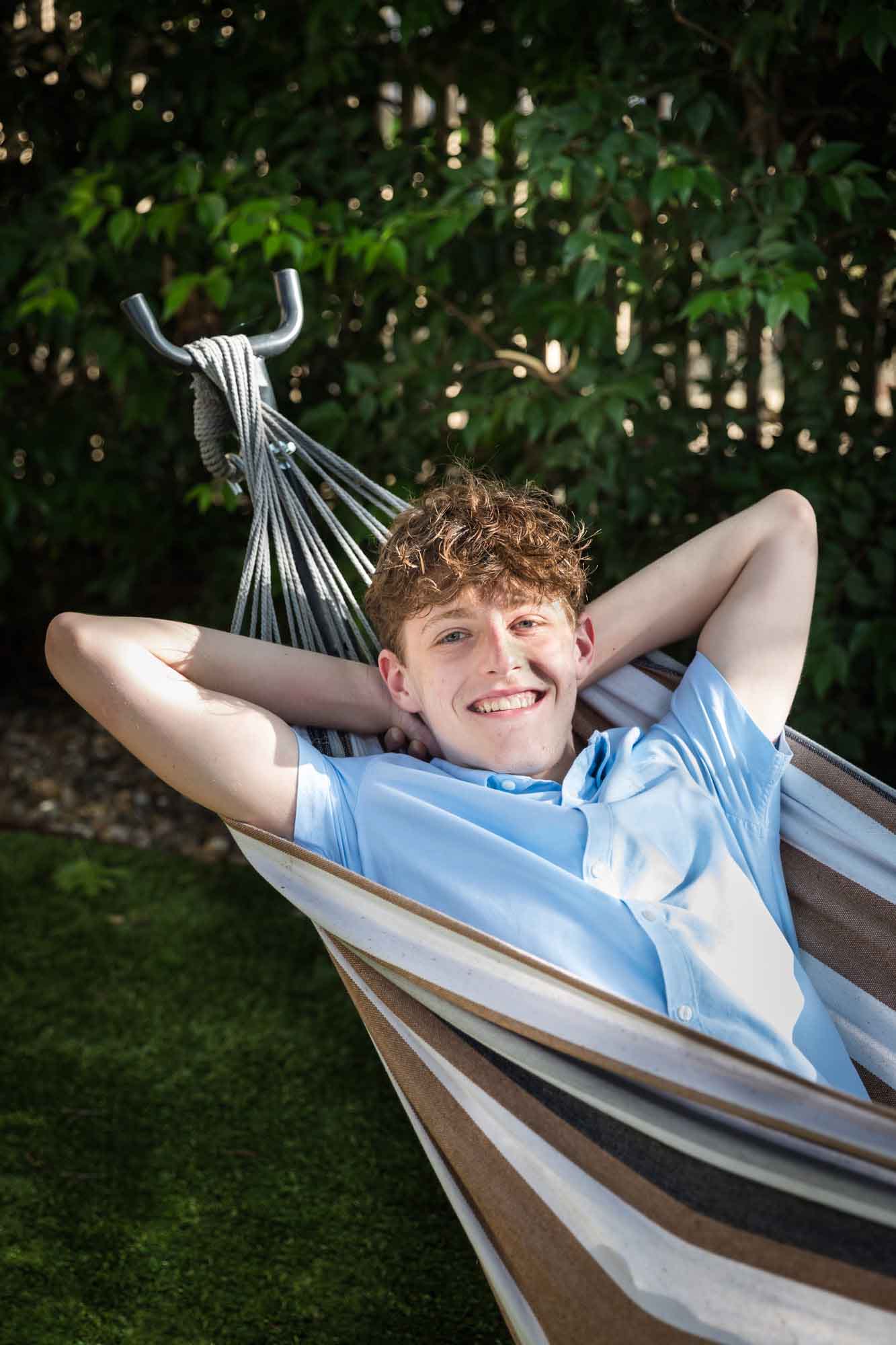 Teenage boy relaxing and smiling in hammock with arms behind his head during a King William family portrait