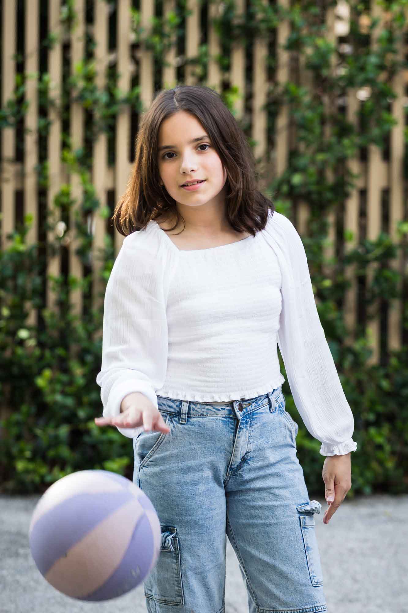 Teenage girl wearing white blouse and jeans bouncing basketball during a King William family portrait