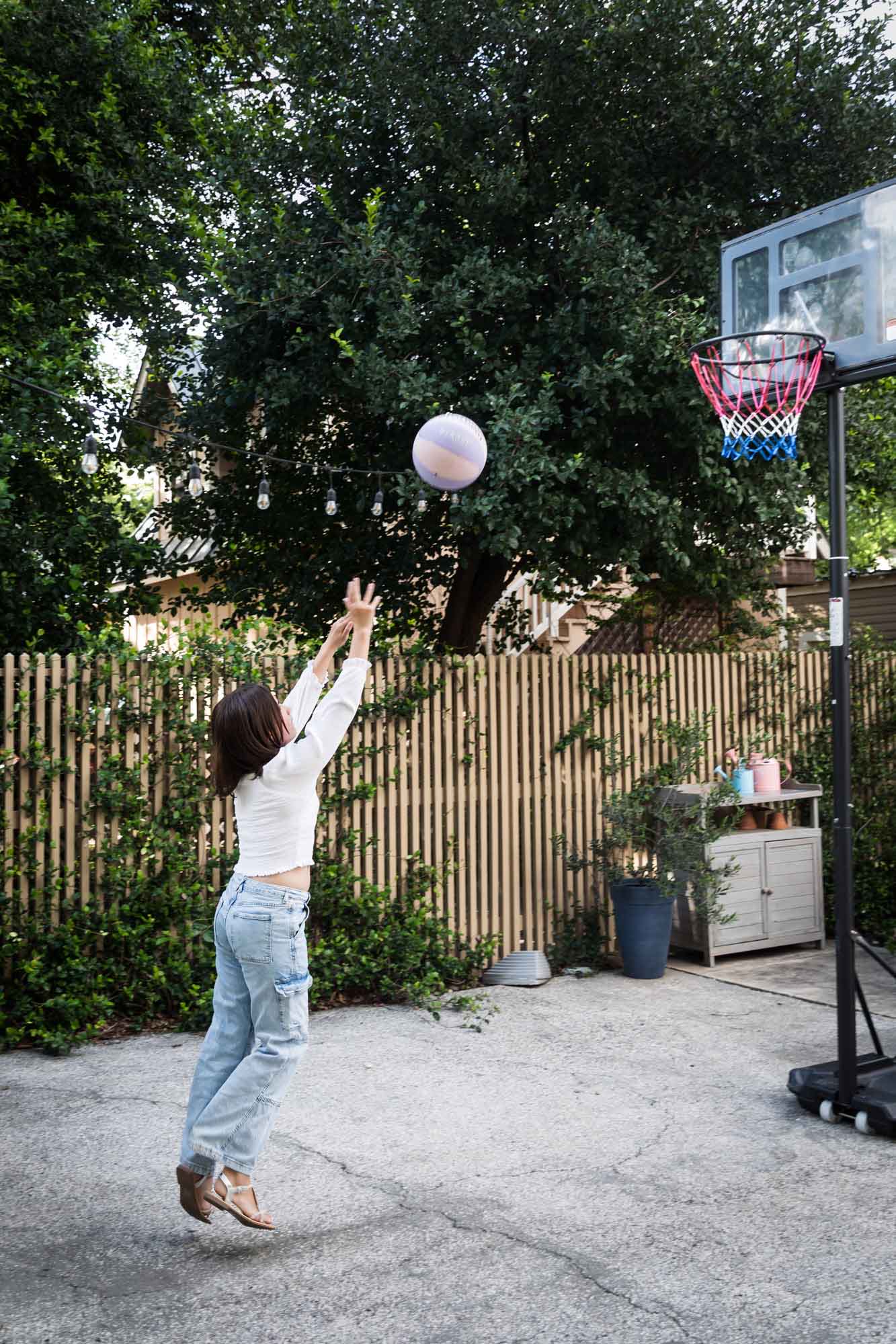 Teenage girl wearing white blouse and jeans shooting basketball during a King William family portrait