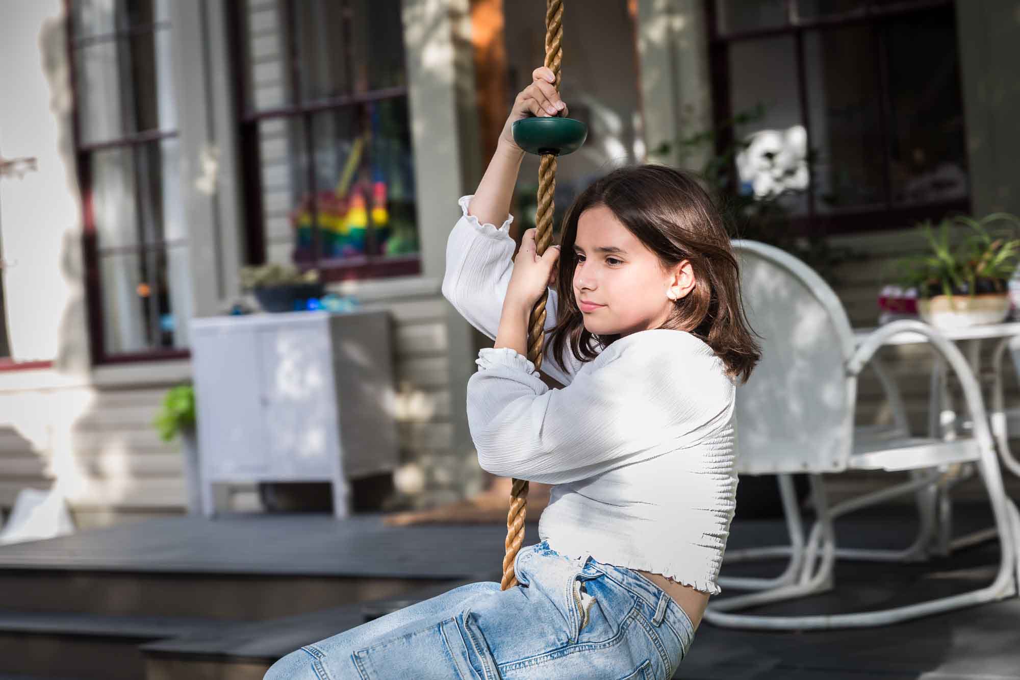 Teenage girl wearing white blouse and jeans standing on swing during a King William family portrait