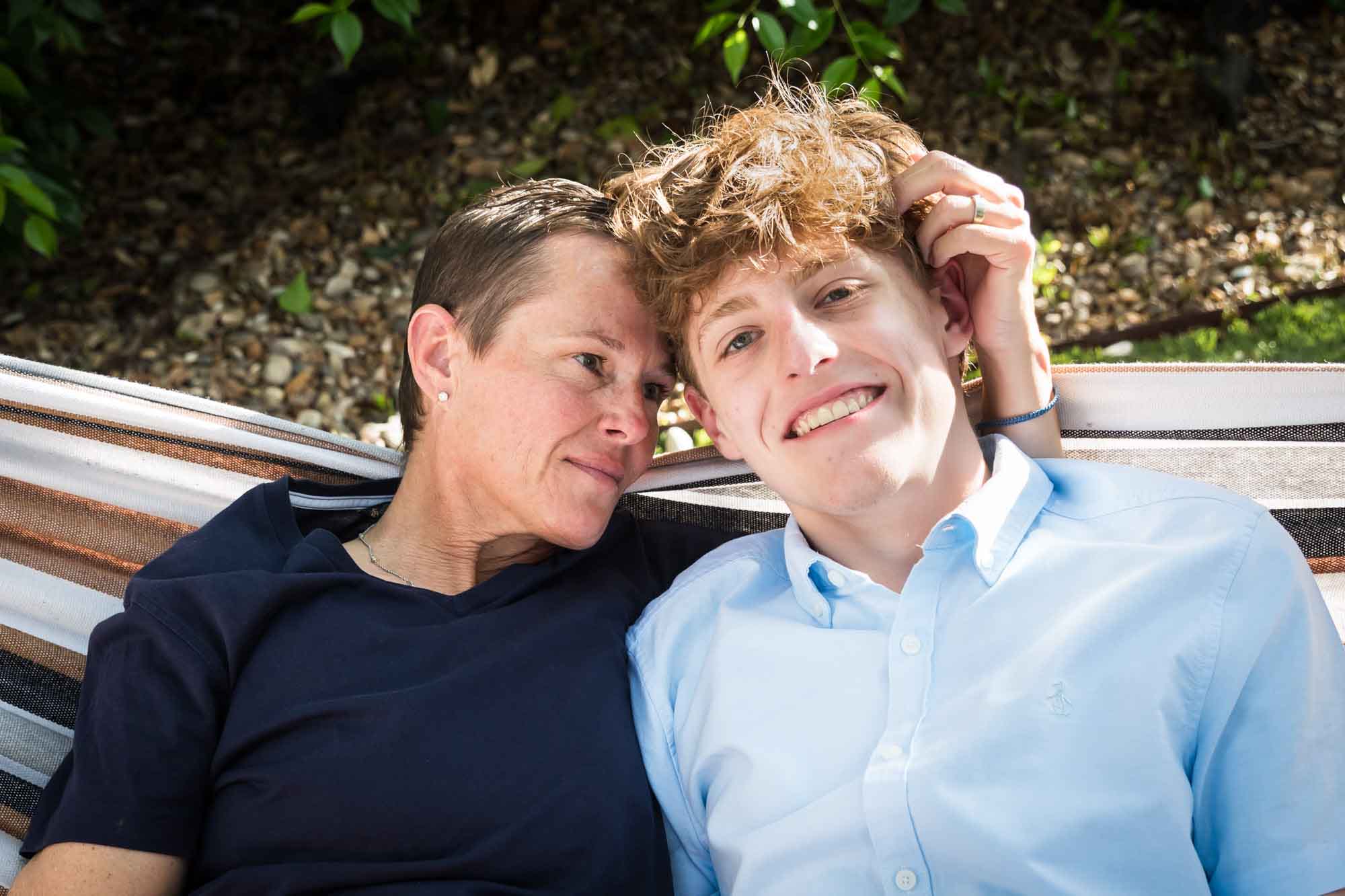 Mother wearing navy t-shirt seated in hammock with teenage son wearing blue shirt during a King William family portrait
