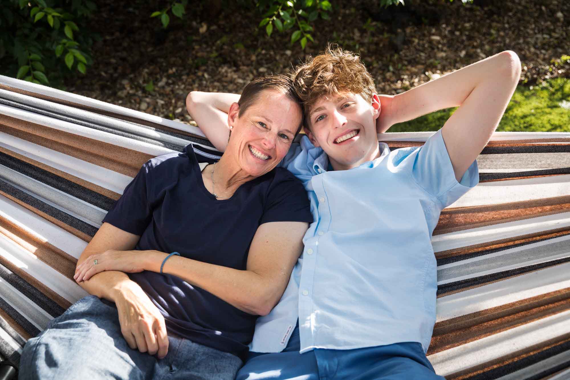 Mother wearing navy t-shirt seated in hammock with teenage son wearing blue shirt during a King William family portrait