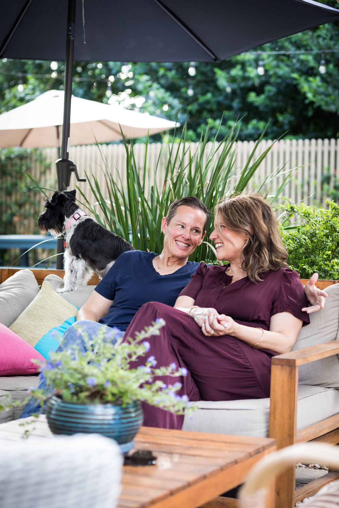 Two women seated on sofa with dog with umbrella in background during a King William family portrait