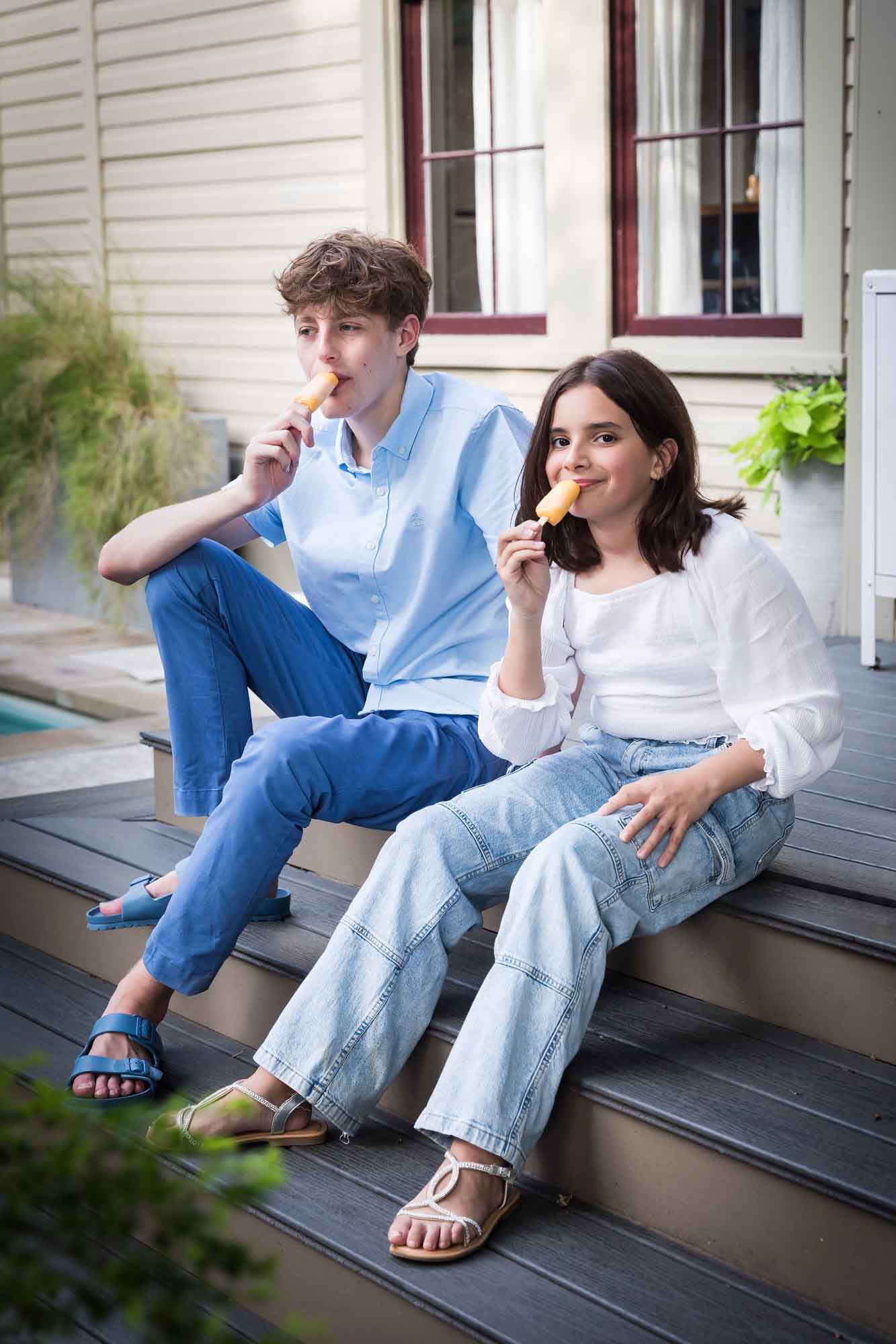 Teenage boy and girl seated on porch eating popsicles during a King William family portrait