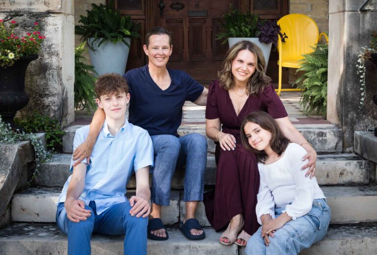 LGBTQ family of two women and two teenage children posed on steps of home during a King William family portrait