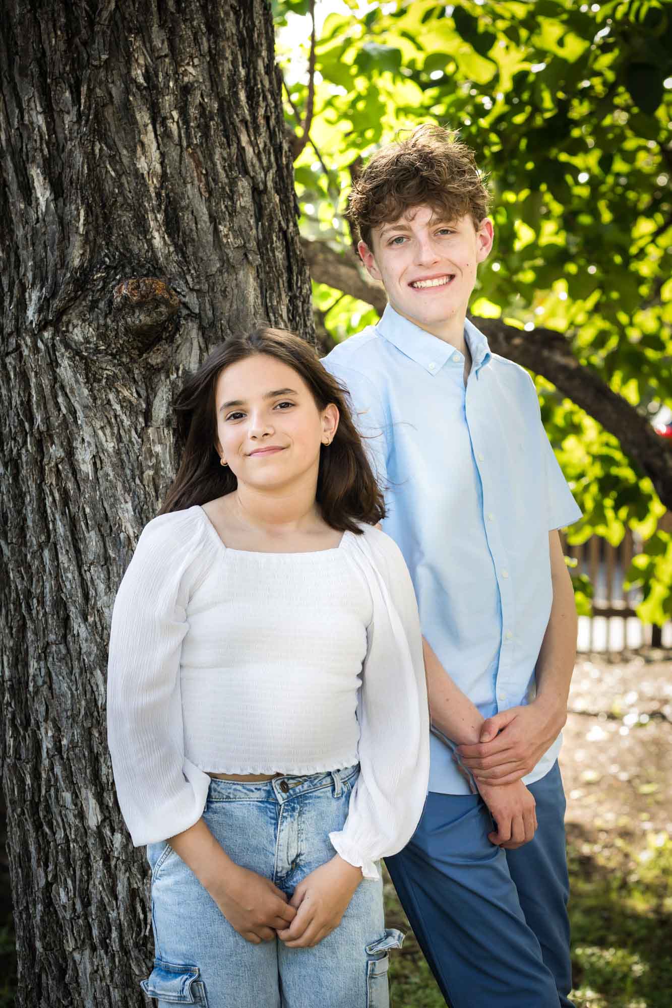 Teenage boy and girl standing in front of large tree with arms at side during a King William family portrait