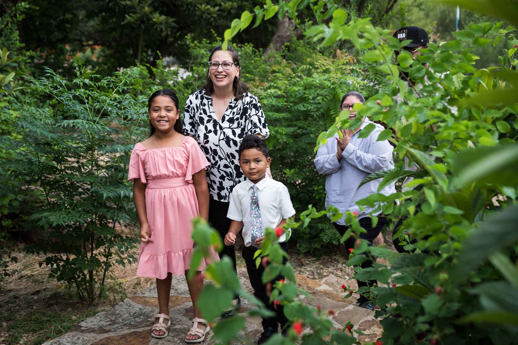 Little boy and girl and two female friends coming out of bushes after proposal
