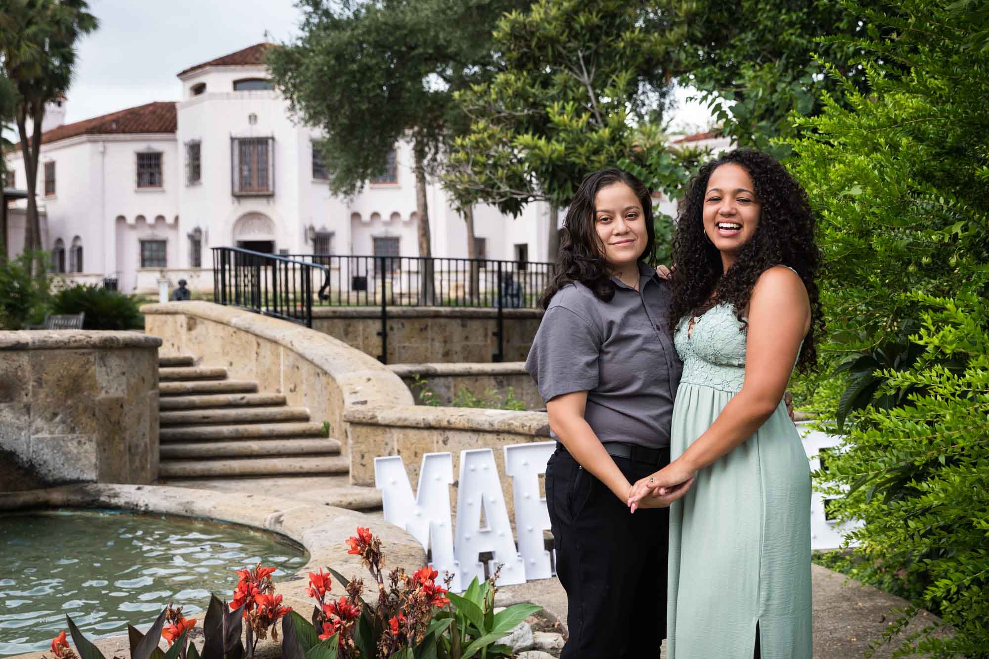 Two women holding hands in front of McNay Art Museum mansion for an article about McNay Art Museum proposal tips