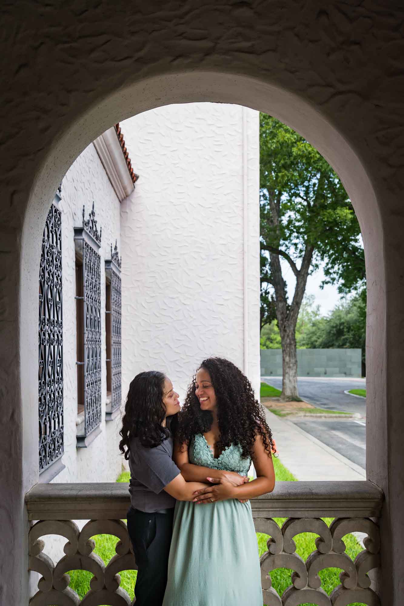 Two women hugging under arch window for an article about McNay Art Museum proposal tips